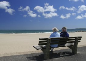 two people sitting on a bench looking at the sea