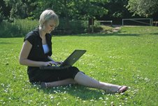 lady sitting on grass using laptop