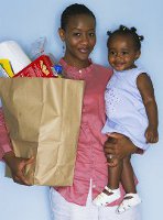 lady carrying a small child and grocery bag